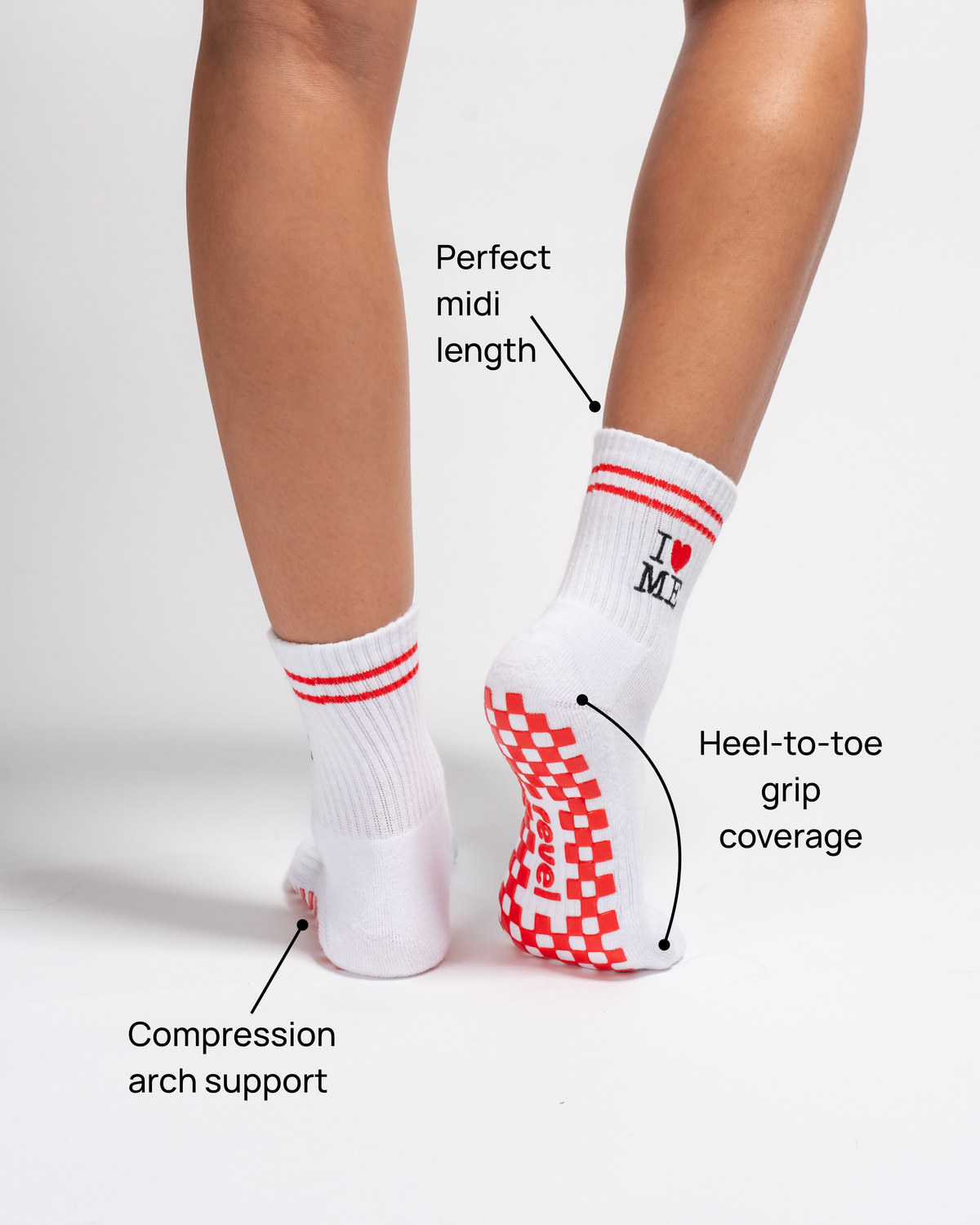 A person wears Revel Athletic’s The New York Grip Sock—white with red accents and non-slip soles—perfect for yoga or Pilates. Text highlights its perfect midi length, full heel-to-toe grip coverage, and compression arch support. The socks read “I ♥ ME.”.