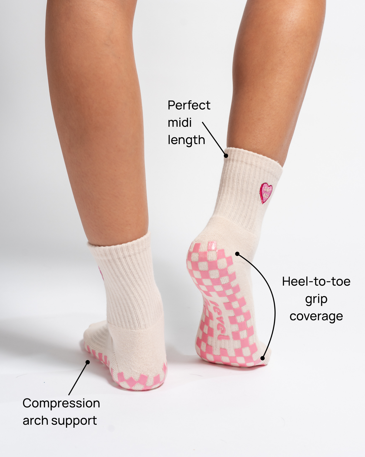 A person wearing The Sweet Nothings Grip Sock by Revel Athletic in beige, featuring pink non-slip grips; labels highlight its midi length, heel-to-toe grip coverage, and compression arch support.