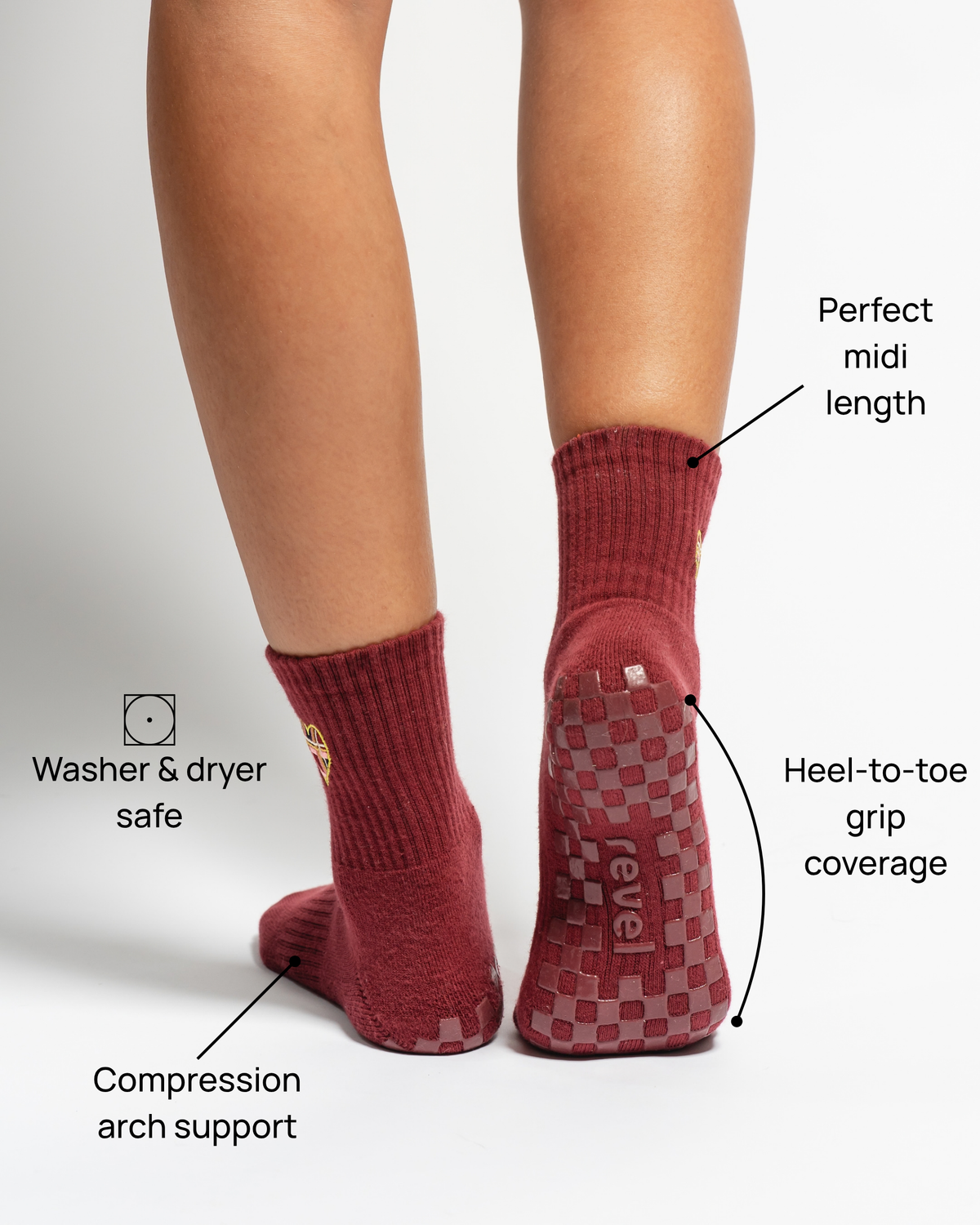 Wearing The Sweetheart socks by Revel Athletic, a person enjoys maroon crew-length GripGrid socks designed for Pilates, featuring arch support and heel-to-toe checkered grip with “revel” on the sole; they’re washer and dryer safe.