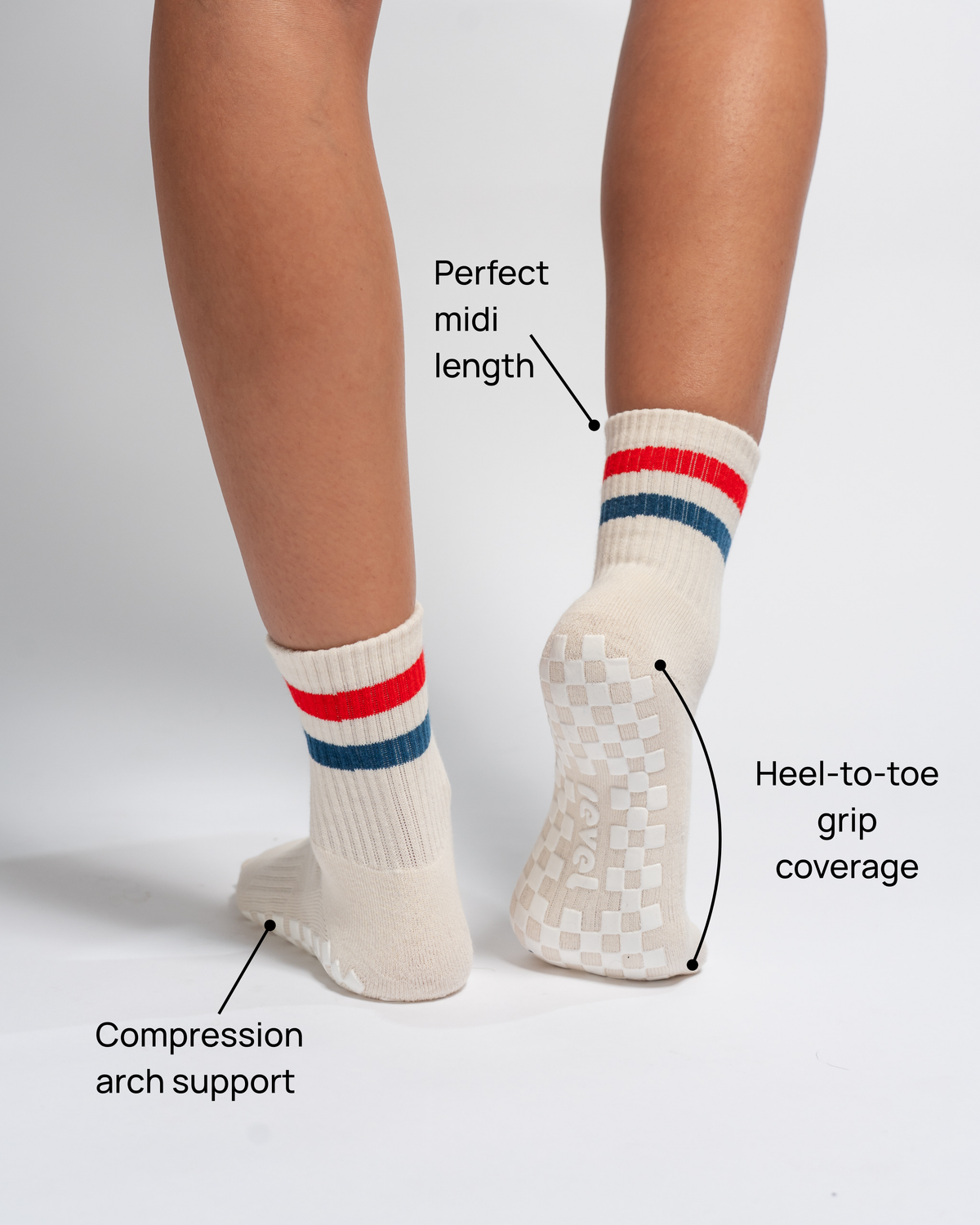Two feet in Revel Athletic’s The Miss Americana Grip Sock in cream, featuring red and blue stripes. Text highlights the sock’s midi length, compression arch support, and full heel-to-toe grip coverage on the sole—making them ideal non-slip socks for enhanced stability. Set against a plain white background.