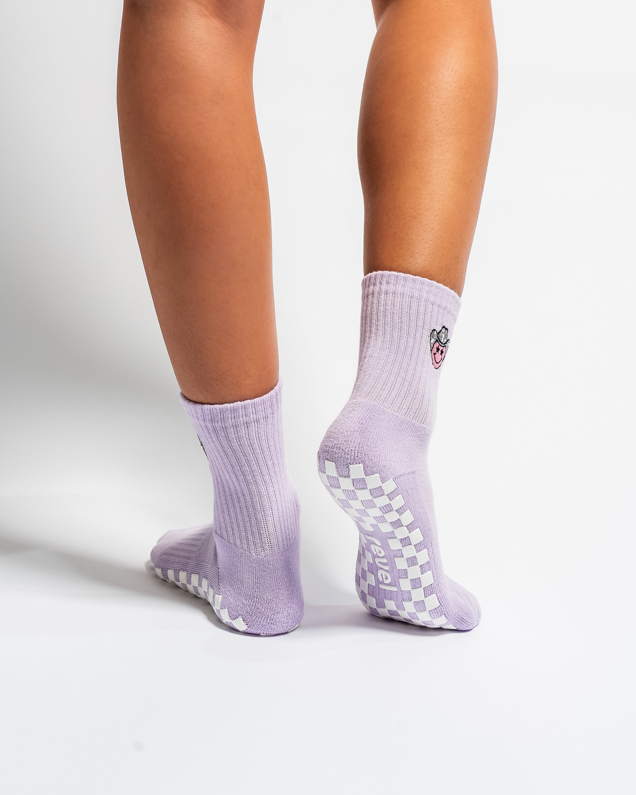 Lavender Austin grip socks with a cowboy-hat smiley face embroidery and a white non-slip traction sole