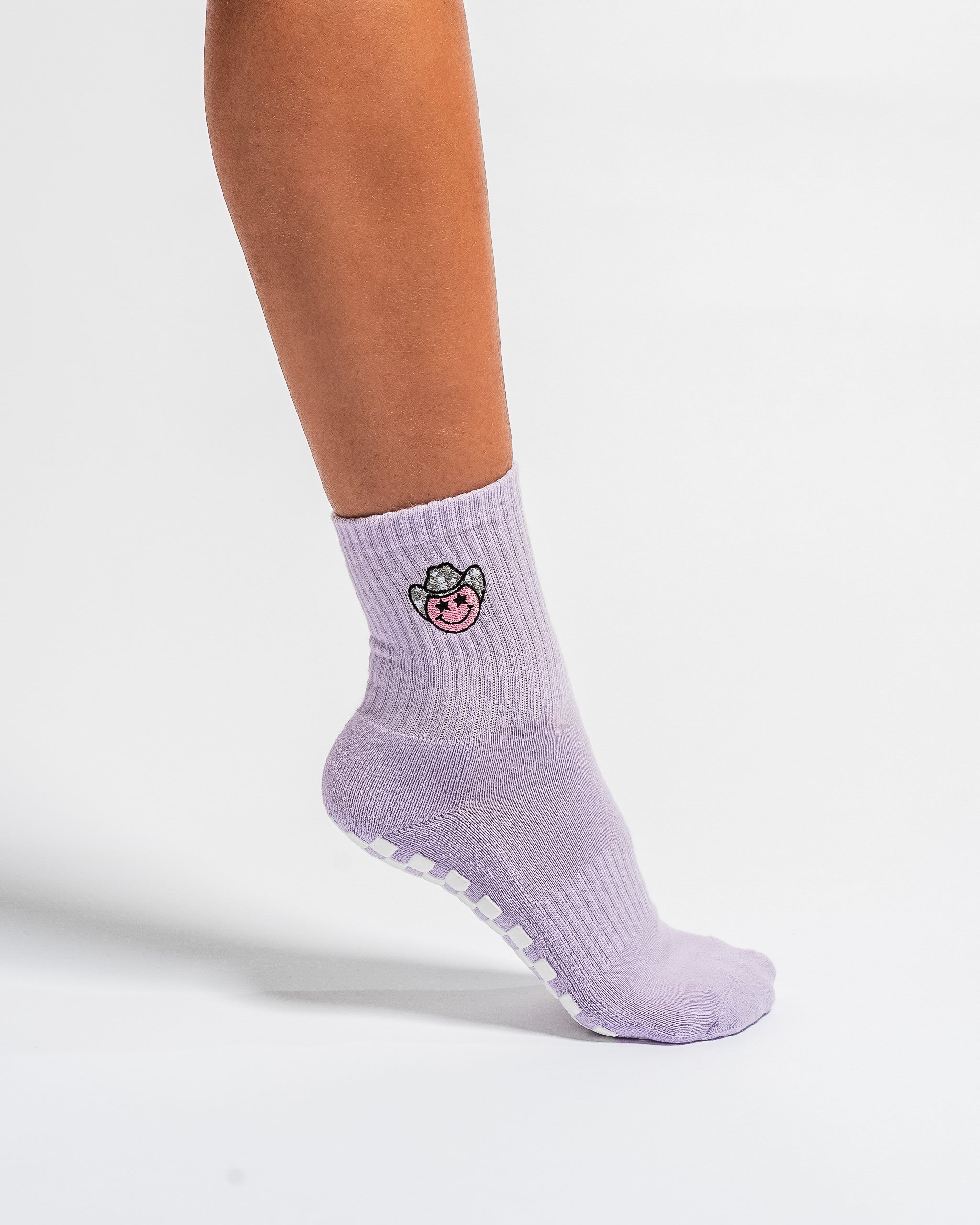 Lavender Austin grip socks with a cowboy-hat smiley face embroidery and a white non-slip traction sole