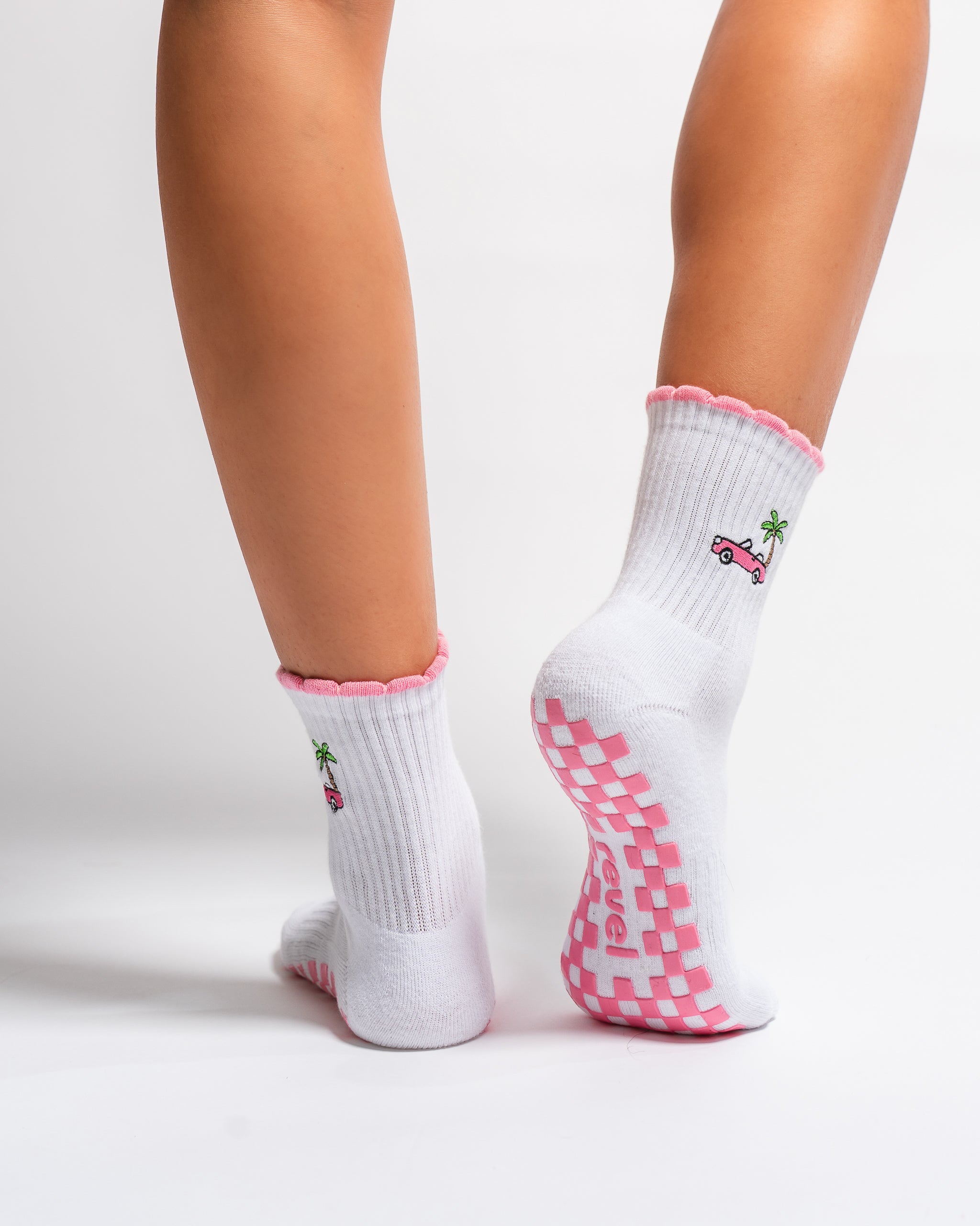 White Los Angeles grip socks with a pink scalloped cuff, pink convertible and palm-tree embroidery, and a pink non-slip patented grip sole