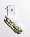 Introducing The Extra Dirty Grip Sock by Revel Athletic: a white crew sock featuring green and white checkerboard grips on the soles for superior traction during Barre, Pilates, or Yoga, and accented with a small embroidered olive (complete with toothpick) near the top.