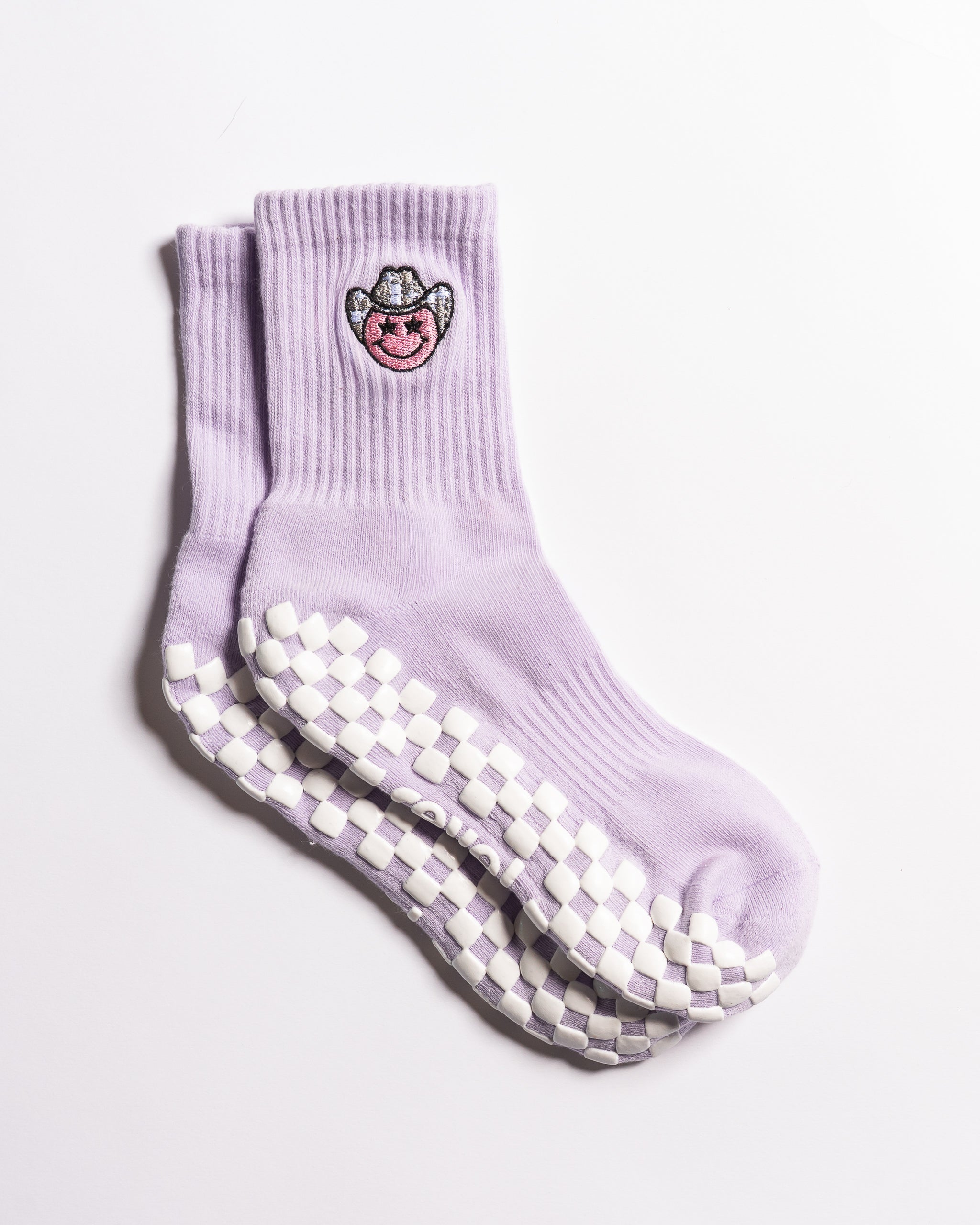 Lavender Austin grip socks with a cowboy-hat smiley face embroidery and a white non-slip traction sole