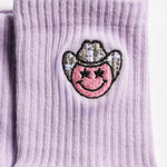 Lavender Austin grip socks with a cowboy-hat smiley face embroidery and a white non-slip traction sole