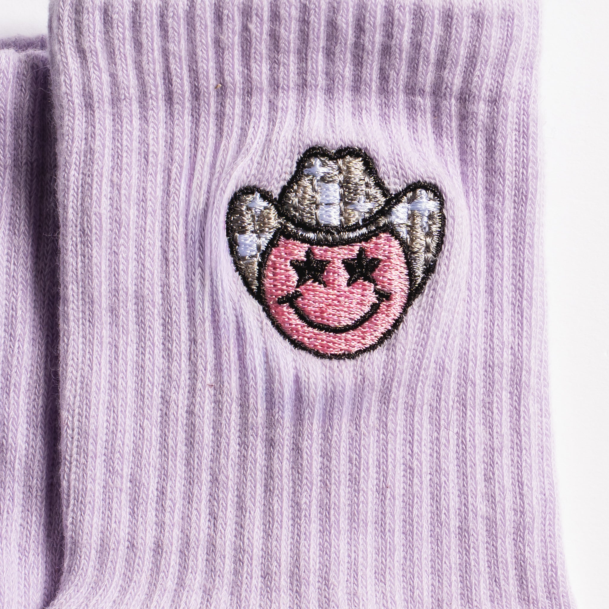 Lavender Austin grip socks with a cowboy-hat smiley face embroidery and a white non-slip traction sole