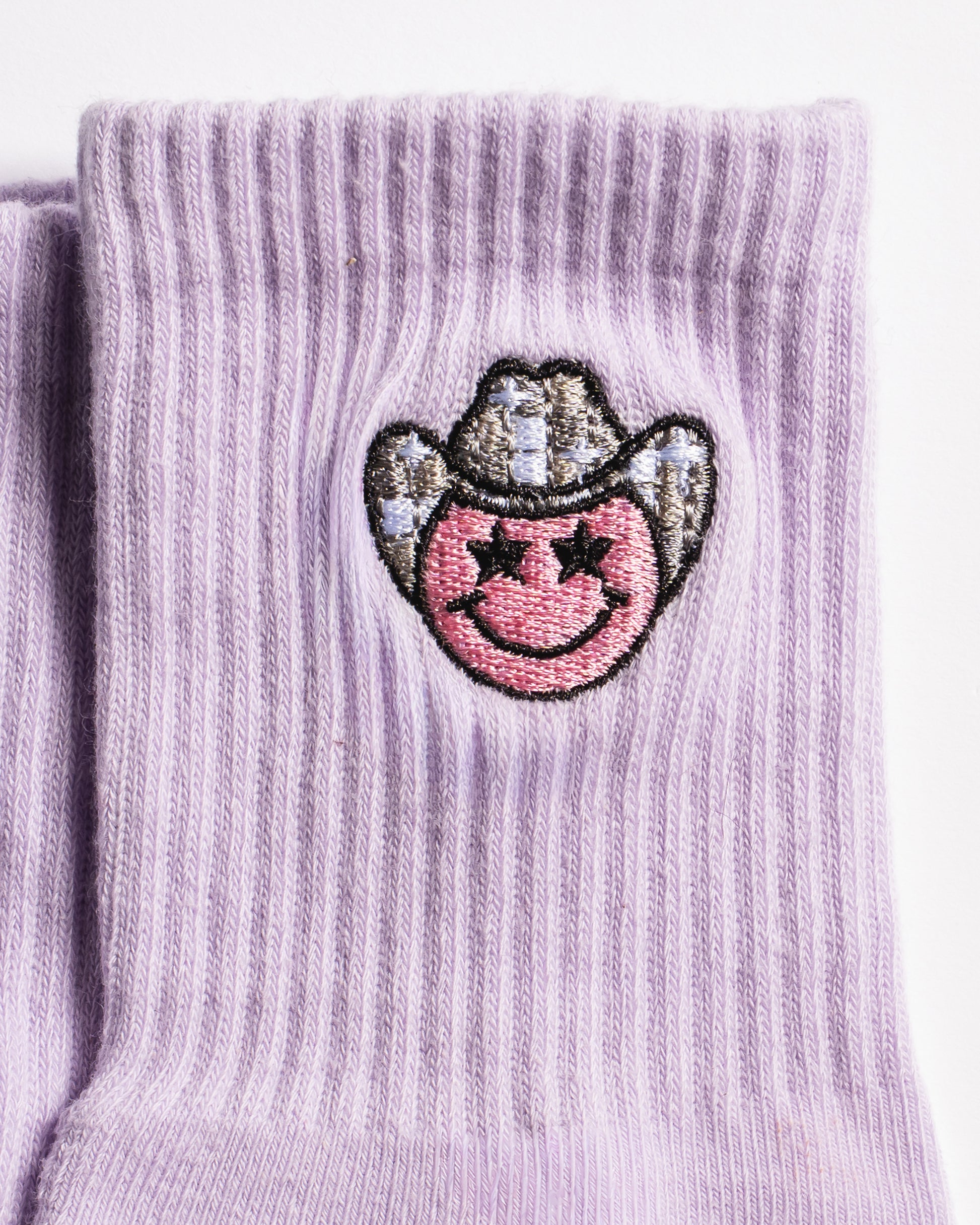 Lavender Austin grip socks with a cowboy-hat smiley face embroidery and a white non-slip traction sole