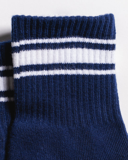 Close-up of two folded Revel Athletic The Country Club Grip Sock (Navy) socks with two white and navy blue stripes near the top. The texture of the knitted fabric is clearly visible.
