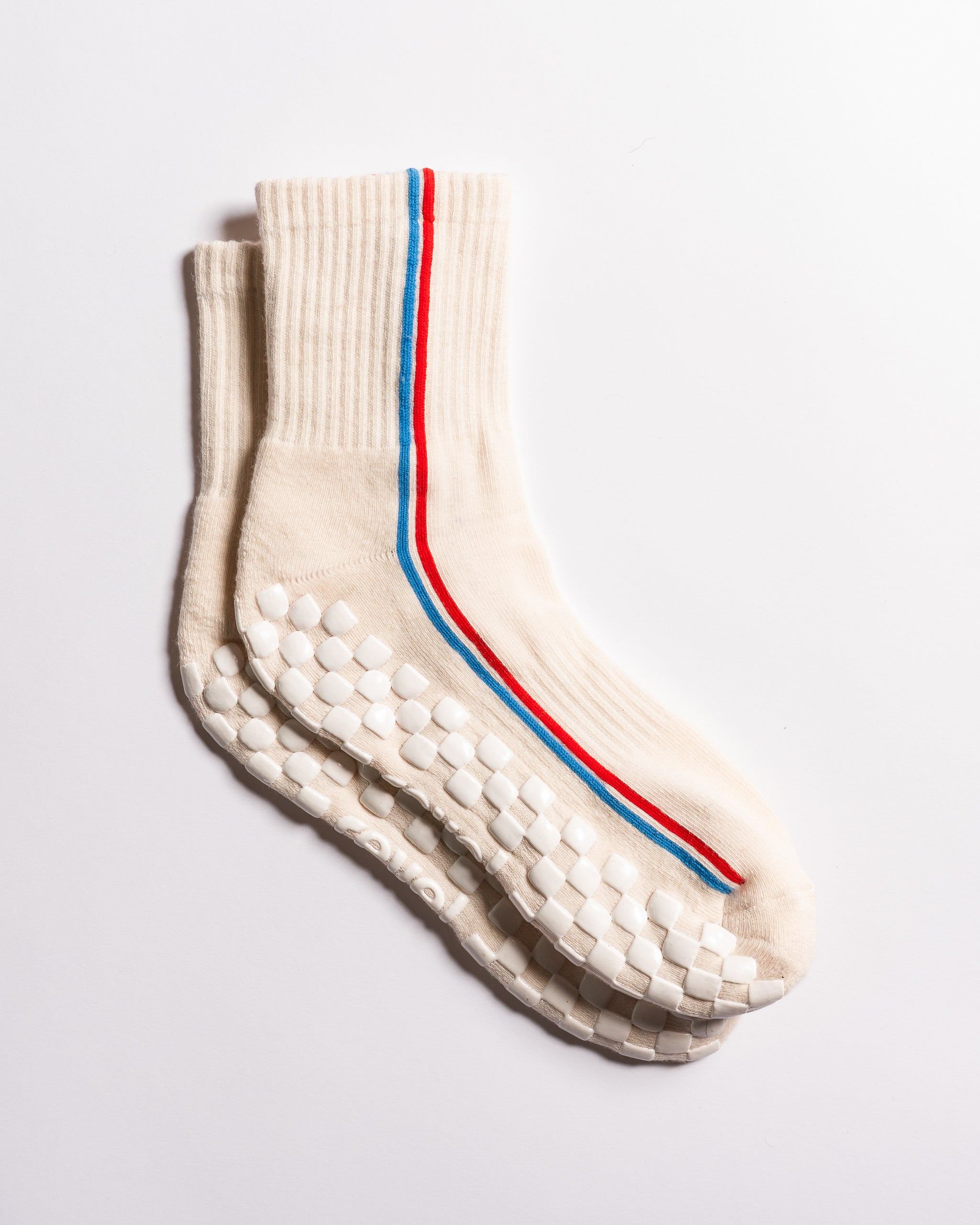 Cream Chicago grip socks with vertical red and blue side stripes and a white non-slip patented grip sole