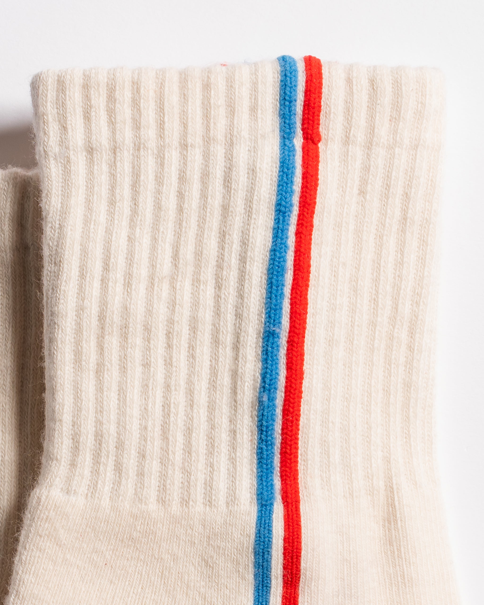 Cream Chicago grip socks with vertical red and blue side stripes and a white non-slip patented grip sole