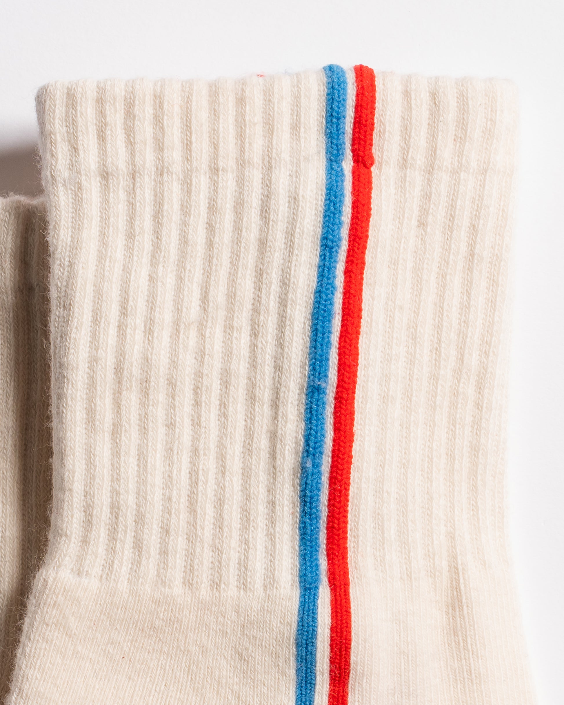 Cream Chicago grip socks with vertical red and blue side stripes and a white non-slip patented grip sole