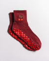 The Very Cherry Grip Sock by Revel Athletic features a delicate cherry embroidery on the ankles and red rubber non-slip patterns on the soles, making them a stylish choice for Pilates. Shown here in maroon and placed against a white background.