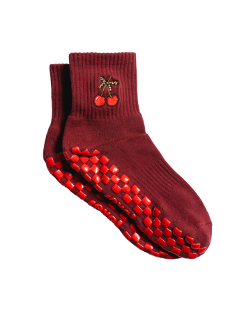 Pair of maroon grip socks with cherry embroidery near the top and red rubber grip dots on the soles, displayed on a white background—ideal pilates socks for added stability and style.