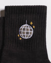 A close-up of The All Nighter Grip Sock by Revel Athletic—a black grip sock ideal for yoga or Pilates, adorned with an embroidered silver disco ball and four small yellow stars.