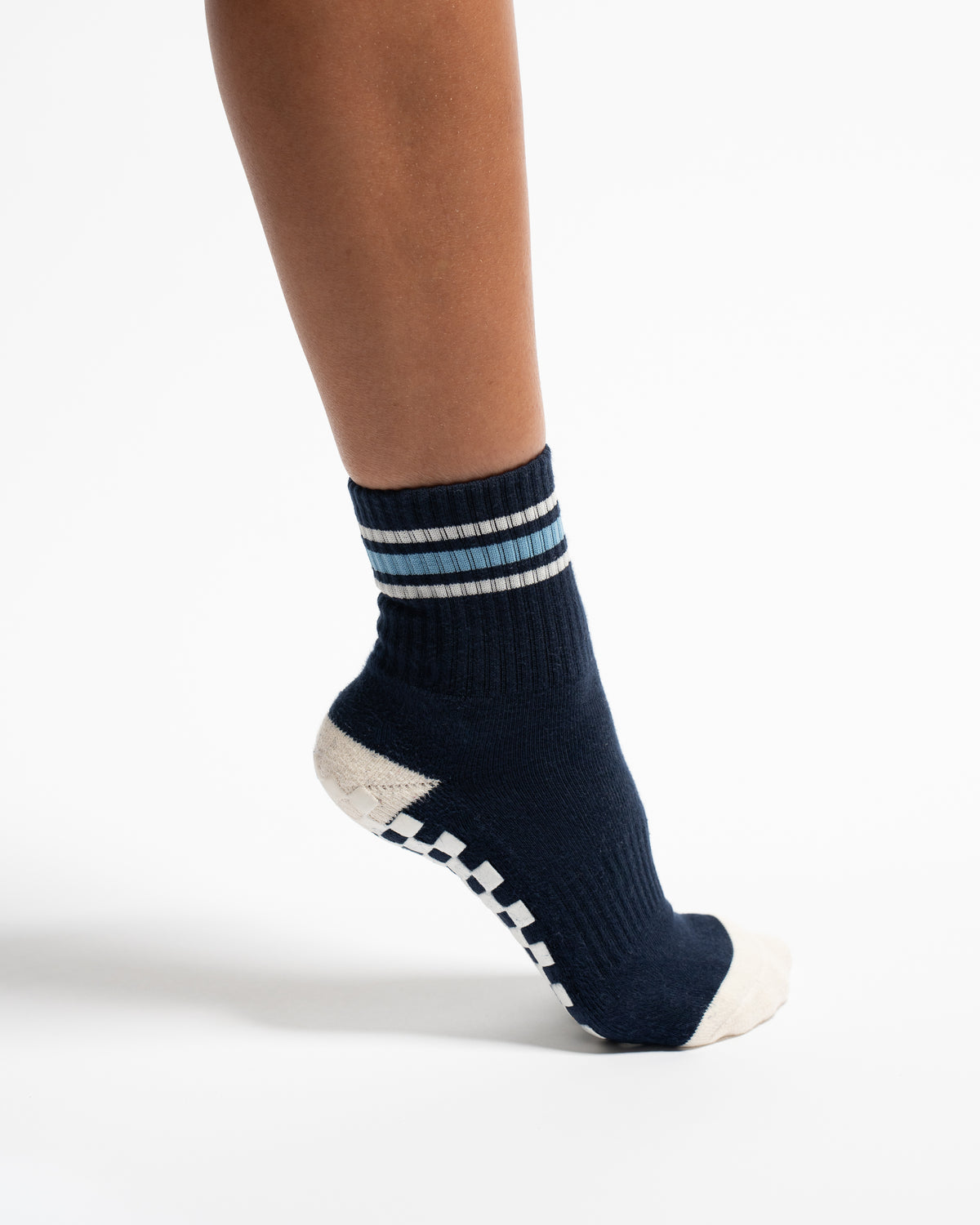 The MVP by Revel Athletic is a navy blue crew-length athletic sock featuring light blue and white stripes at the cuff and a checkered grip pattern on the sole.