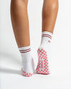 Revel Athletic The Sportyish white crew socks with maroon stripes, featuring a pink-and-white checkered non-slip grip on the soles.