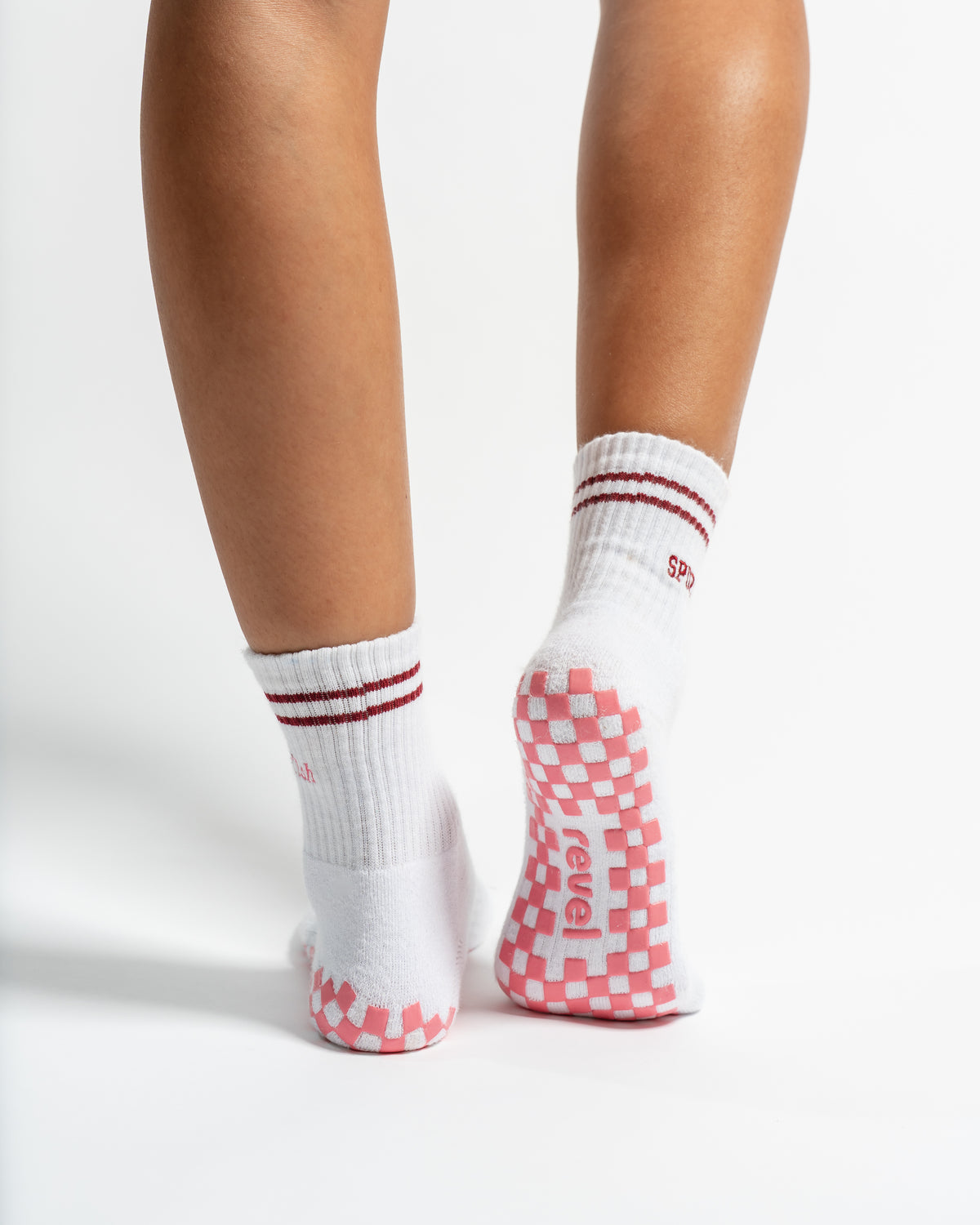 Revel Athletic The Sportyish white crew socks with maroon stripes, featuring a pink-and-white checkered non-slip grip on the soles.