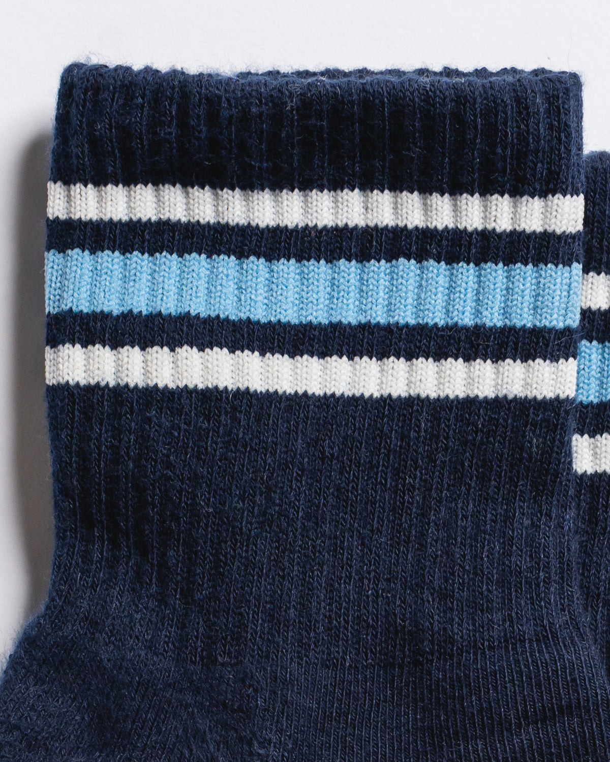 Revel Athletic The MVP navy blue yoga grip socks with white and light blue stripes around the ribbed cuff.
