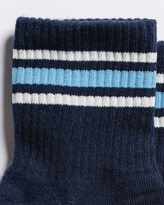 Revel Athletic The MVP navy blue yoga grip socks with white and light blue stripes around the ribbed cuff.