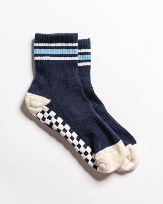 Revel Athletic The MVP navy blue crew socks with light blue and white striped cuffs, featuring a white checkered GripGrid pattern on the soles and toes for improved traction.