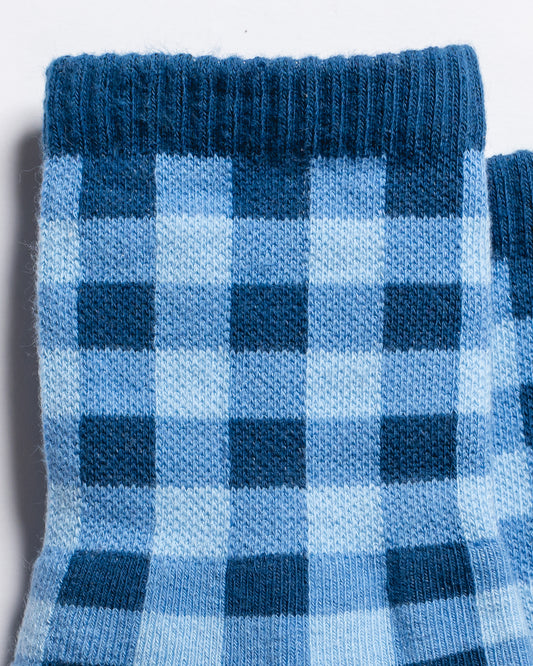 Close-up of The Prep Grip Sock by Revel Athletic in blue gingham. Featuring a ribbed cuff and alternating squares in two shades, these socks showcase a classic plaid design that’s perfect for elevating your everyday style.