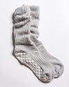 A pair of “The Slouch - Grey” ribbed Pilates grip socks by Revel Athletic, featuring light gray color and textured non-slip grips on the soles, displayed on a white background.