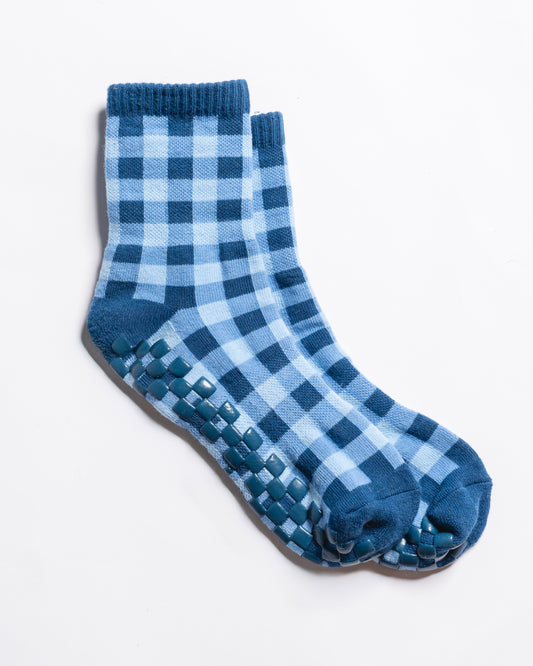Introducing The Prep Grip Sock by Revel Athletic: a pair of blue and light blue checkered socks, channeling classic blue gingham style, with non-slip grips on the soles—ideal for Pilates or barre—shown against a white background.