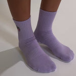 Lavender Austin grip socks with a cowboy-hat smiley face embroidery and a white non-slip traction sole