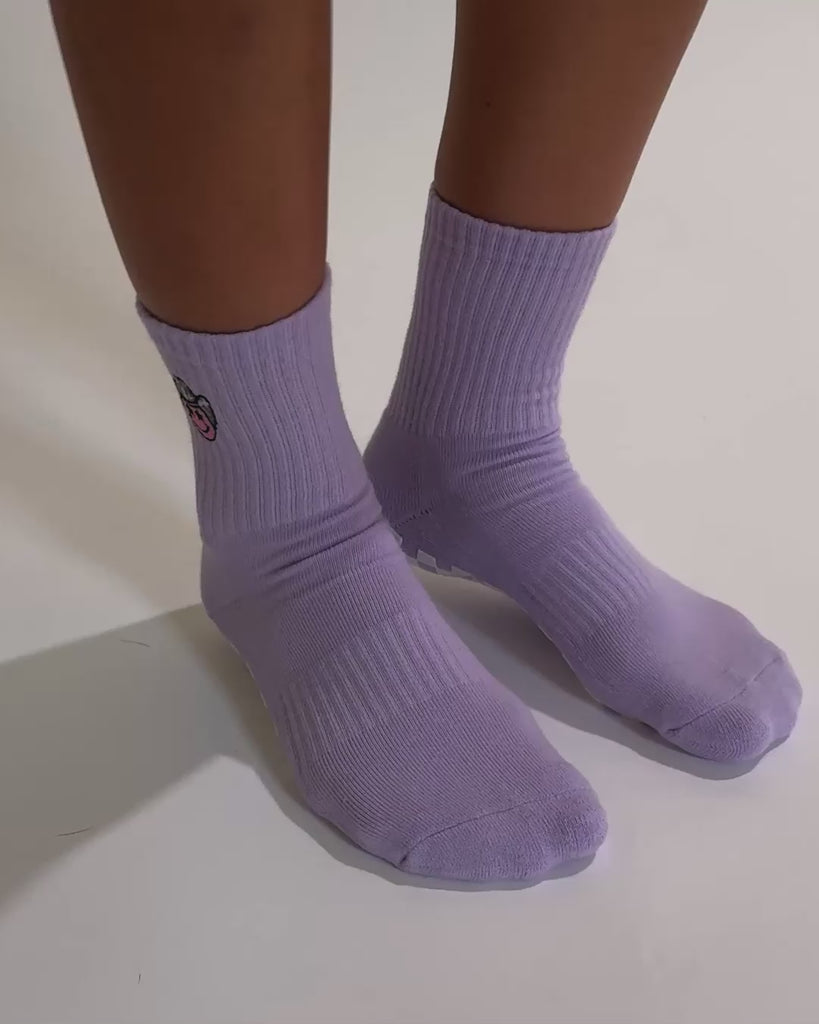 Lavender Austin grip socks with a cowboy-hat smiley face embroidery and a white non-slip traction sole